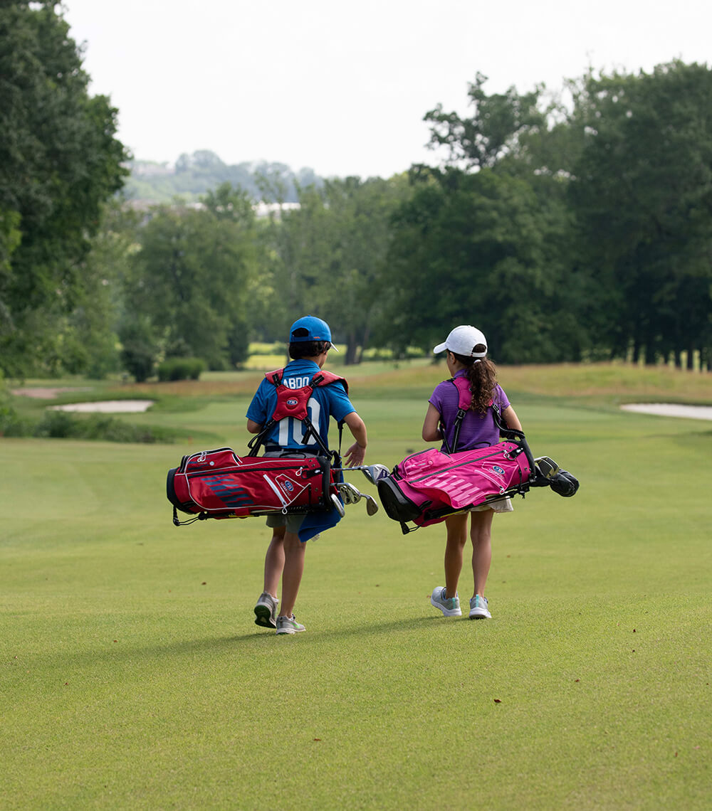 junior golfers carrying golf bags